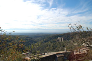 Man blickt in das Tal vom französchien Schwarzwald aus und sieht im Hintergrund die Pyrenäen. Das Chateau steht im Vordergrund unten rechts im Bild.