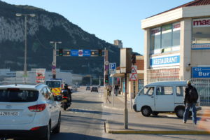 Die Straße in das Zentrum von Gibraltar. Eine Ampel stellt sich auf Rot, wenn ein Flugzeug startet.