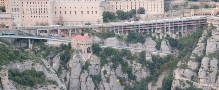 Man sieht das eindrucksvolle Benediktinerkloster Montserrat von einem gegenüberliegenden Felsvorsprung