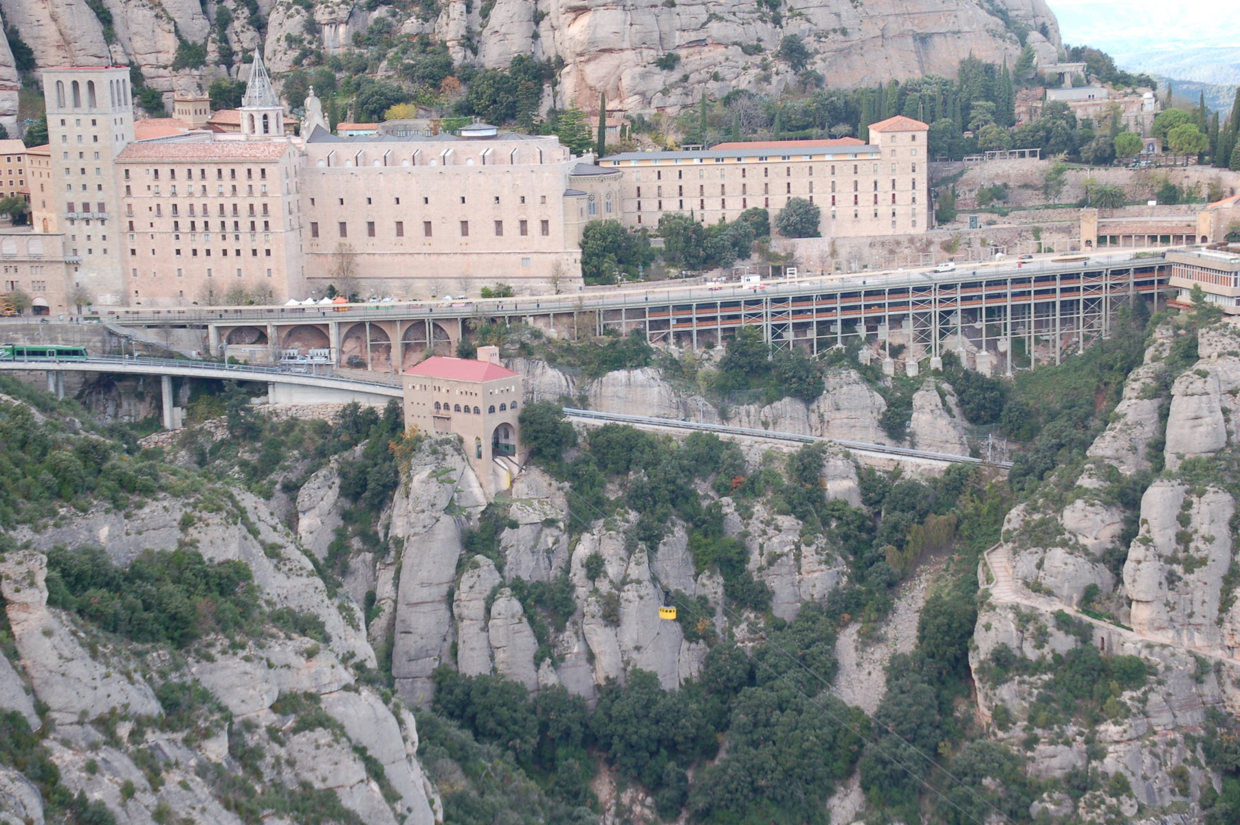 Man sieht das eindrucksvolle Benediktinerkloster Montserrat von einem gegenüberliegenden Felsvorsprung