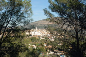 Man sieht die Stadt Parcent im Tal von Pop durch Bäume.