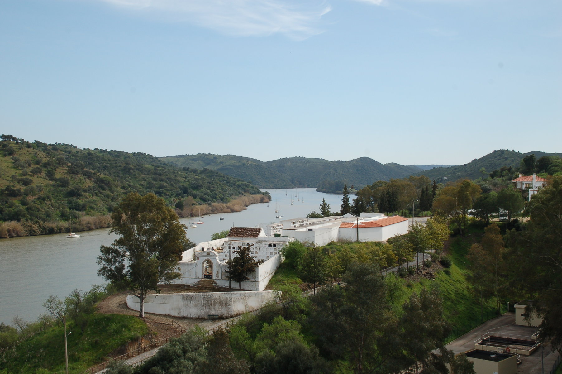 im Vordergrund einige weiß getünchte Gebäude am Flussufer des Guadiana